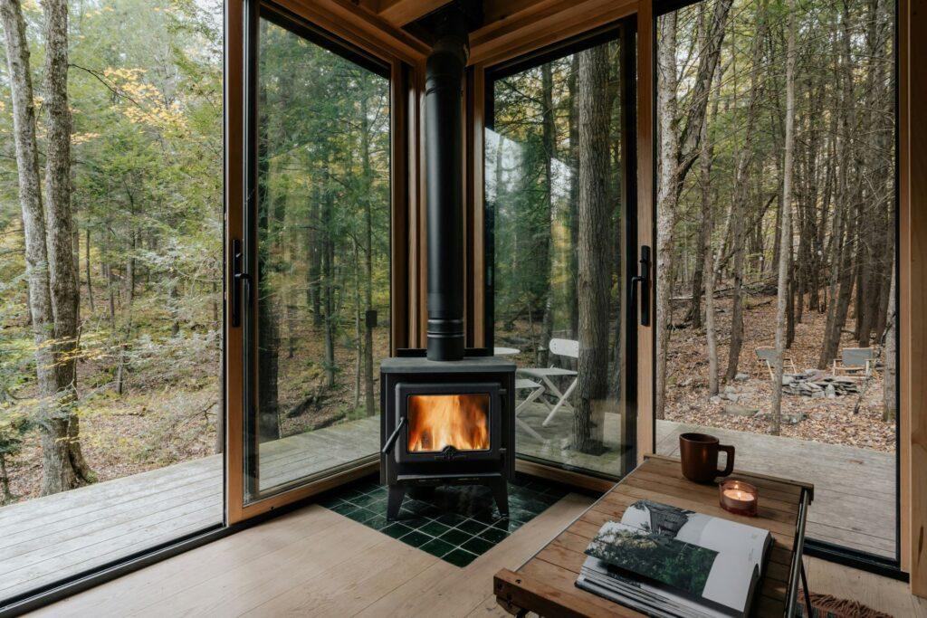 Moderner Holzofen mit Kamin Glasscheibe in einer Glashütte mitten im Wald, mit Blick auf die Natur.