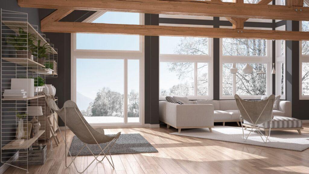 Helles, minimalistisches Wohnzimmer mit einem modernen Couchtisch, einem großen Sofa und Panoramafenstern, die den Blick auf die schneebedeckte Landschaft eröffnen.