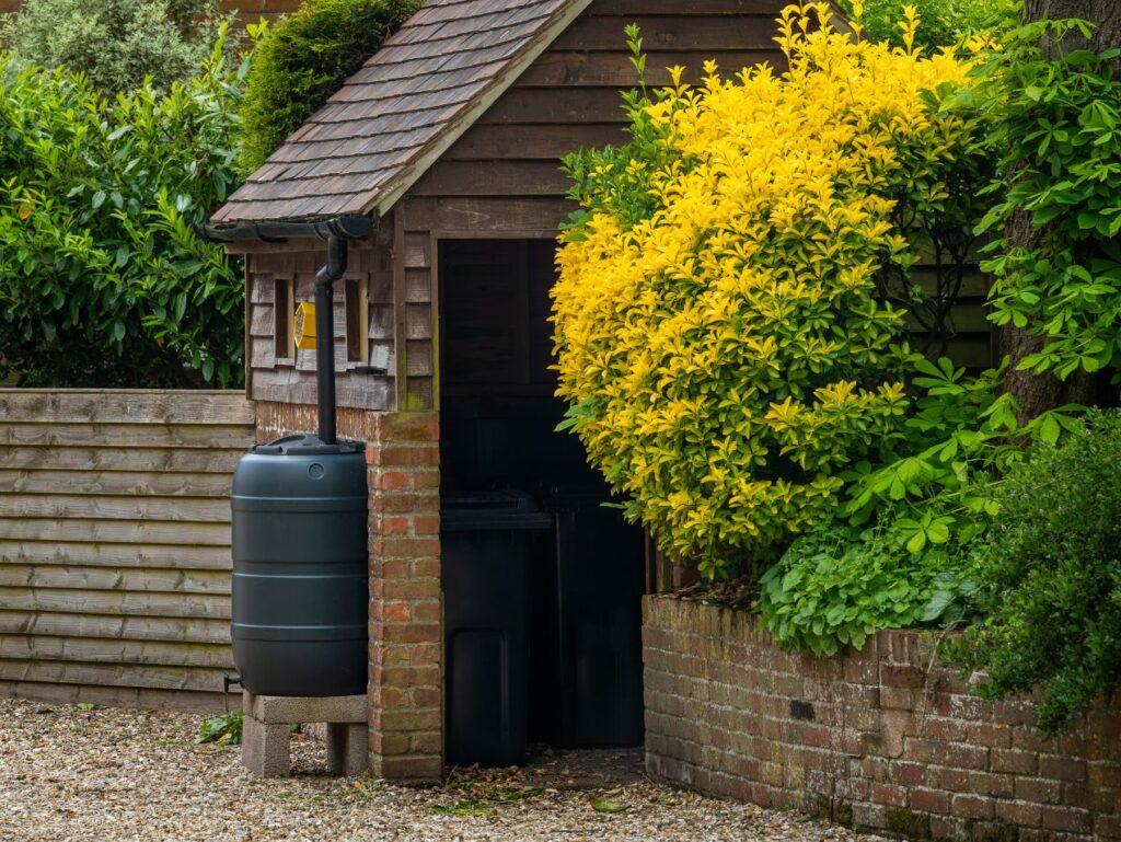 Regenwassertank an einem Gartenhaus mit Fallrohrsystem – effiziente Wasserversorgung für autarke Haushalte mit Trockentrenntoilette